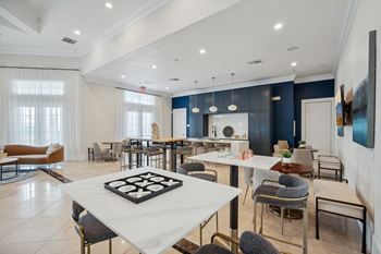 a communal area with tables and chairs and a kitchen and living room at The Falls of Portofino Apartment, Naples, FL
